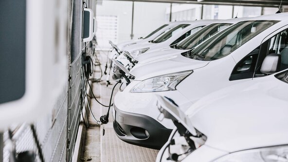 Mehrere weiße Firmenfahrzeuge sind an Wallbox angeschlossen