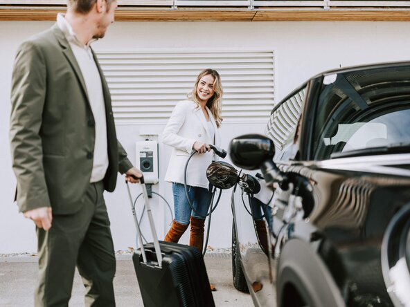 Junges Paar lädt E-Auto an Hotel Wallbox