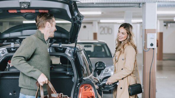 Junges Paar lädt E-Auto an Wallbox in Tiefgarage