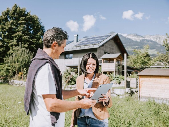 Mann zeigt Frau die eingespeiste Strommenge auf dem Tablet