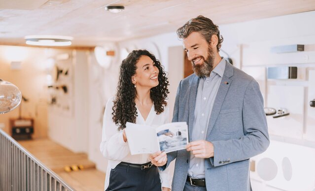 Mann zeigt junger Frau eine Broschüre zur Energieeffizienz