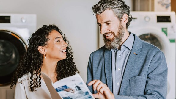 Mann zeigt junger Frau eine Broschüre zur Energieeffizienz