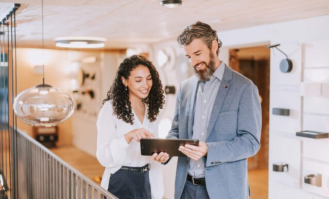 Mann zeigt Frau etwas auf dem Tablet in einem Lampengeschäft