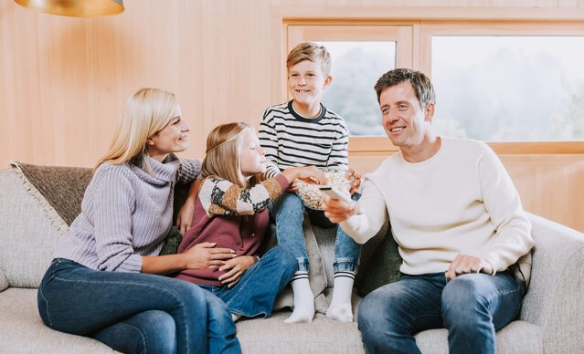 Familie sitzt auf Couch und isst Popcorn