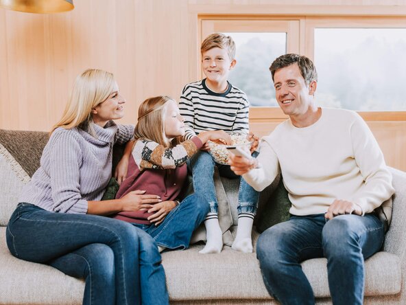 Familie sitzt auf Couch und isst Popcorn