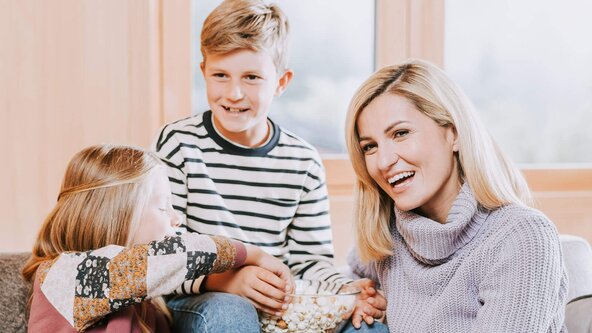 Familie sitzt auf Couch und isst Popcorn