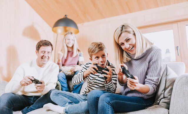 Familie sitzt auf Couch und spielt Playstation