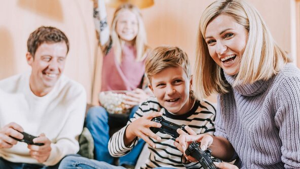 Familie sitzt auf Couch und spielt Playstation