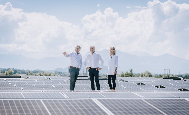 Drei Personen stehen auf dem Dach und begutachten die PV Anlage