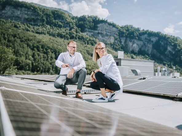 Ein Mann zeigt einer Frau die PV Anlage auf dem Dach