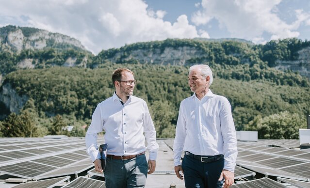 Ein Mann zeigt einem anderen Mann die PV Anlage auf dem Dach