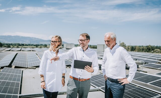 Mann mit Tablet zeigt seinen Kunden die Leistung der PV Anlage