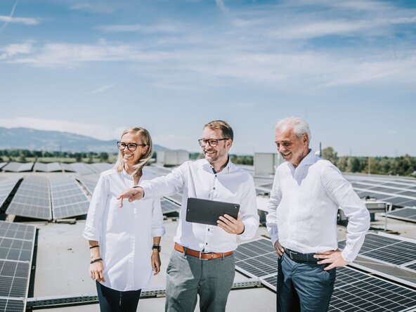 Mann mit Tablet zeigt seinen Kunden die Leistung der PV Anlage