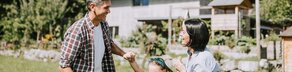 Familie spielt im Garten vor einem Haus mit PV Anlage
