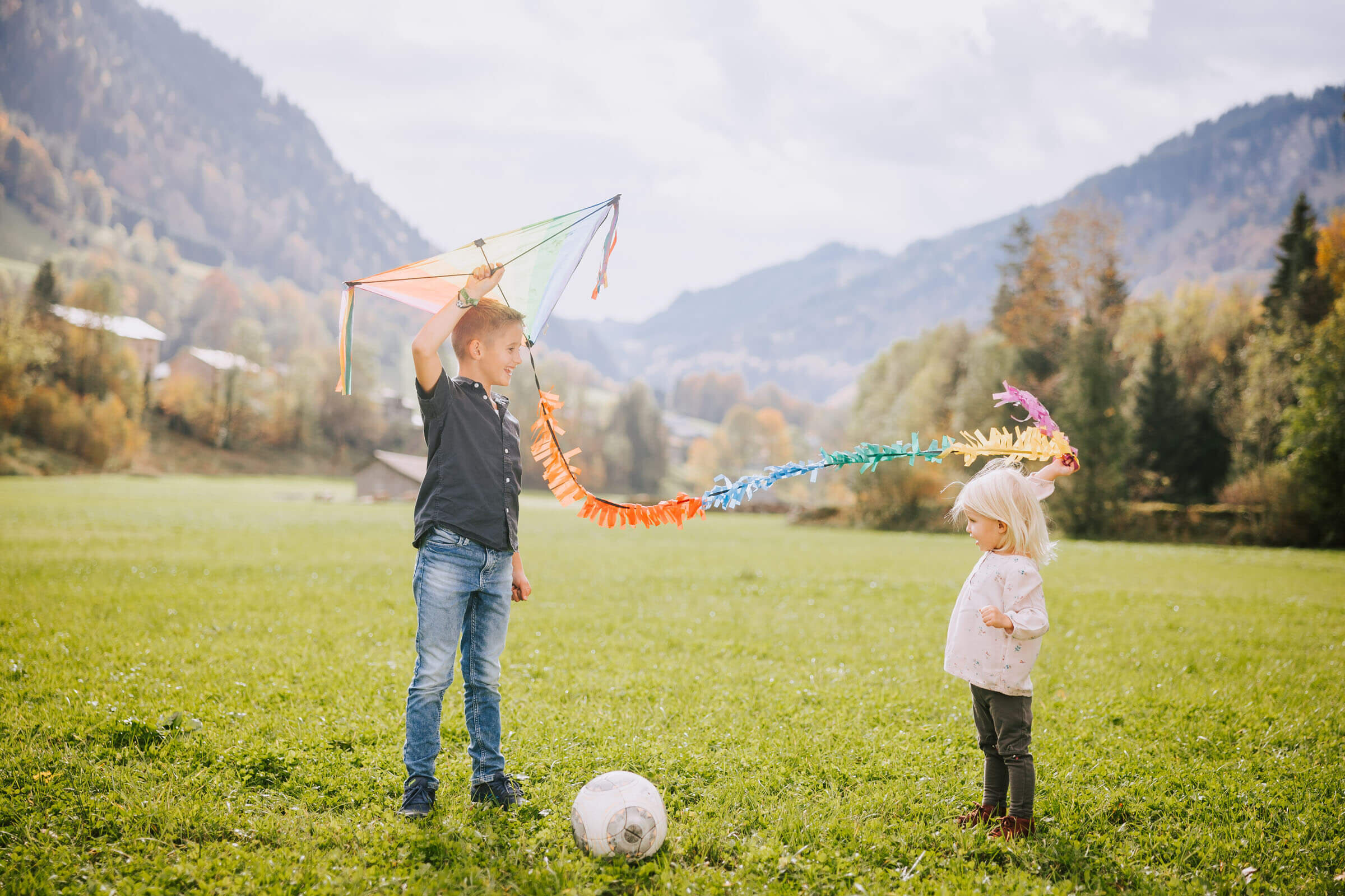 Zwei Kinder spielen mit einem Drachen auf der Wiese