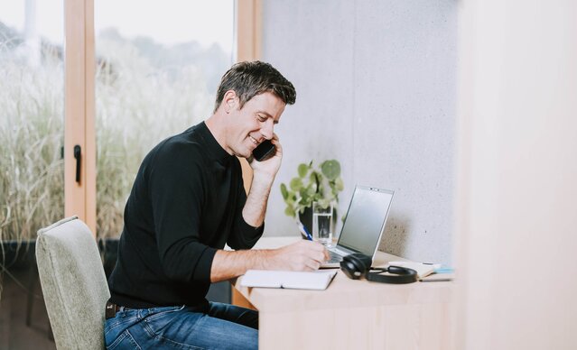 Mann telefoniert mit Handy an Schreibtisch