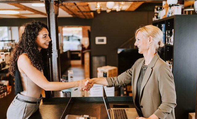 Ladenbesitzerin gibt Kundin die Hand