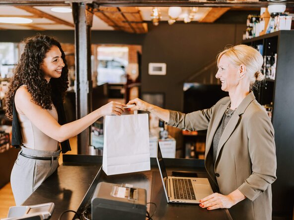 Ladenbesitzerin gibt Kundin eine weiße Tasche