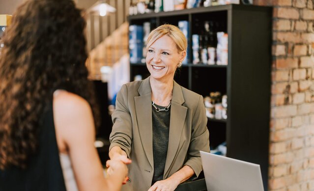 Ladenbesitzerin gibt Kundin die Hand