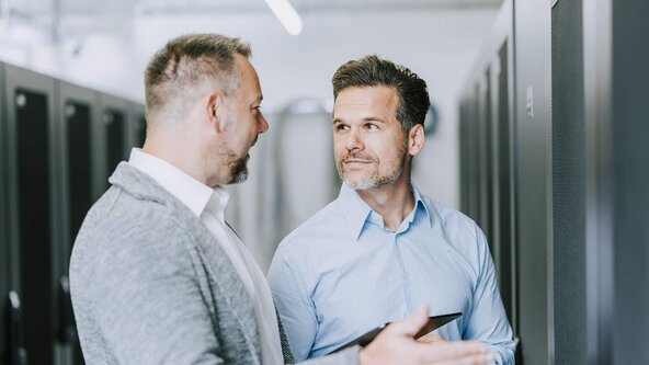 Unternehmer zeigt Kundenbetreuer seinen Serverschrank