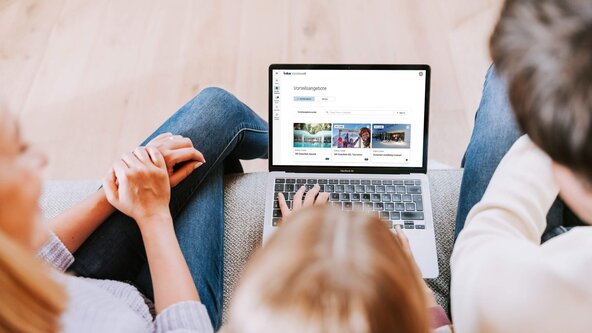 Familie sitzen auf Couchtisch sieht in Laptop