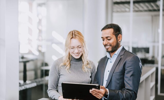 Mann und Frau im Büro sehen aufs Tablet