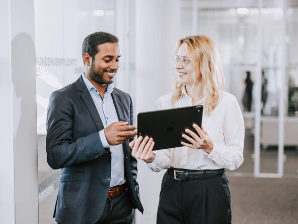 Mann und Frau im Büro sehen aufs Tablet