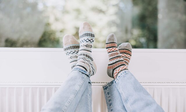 Zwei paar Füße mit Wollsocken auf einem Heizkörper