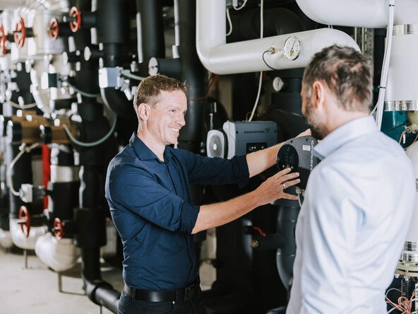 Zwei Männer diskutieren in einem Heizraum